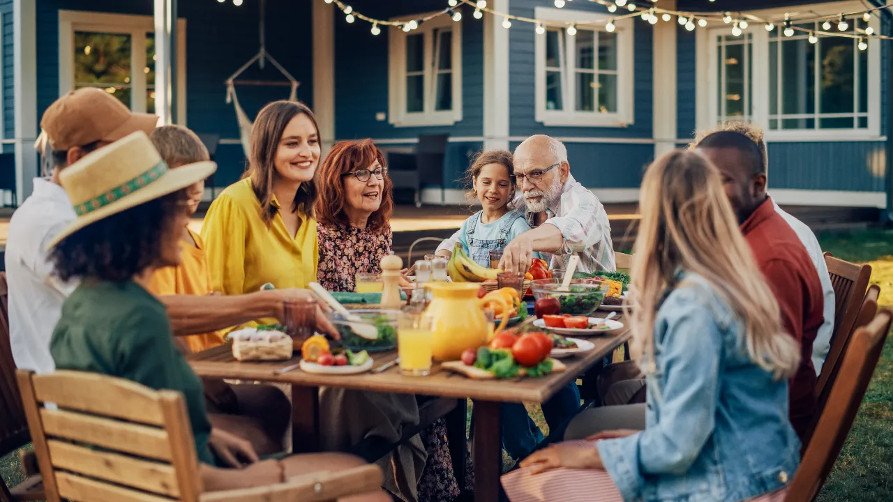 Multigenerational friends and family sharing an outdoor meal at dusk